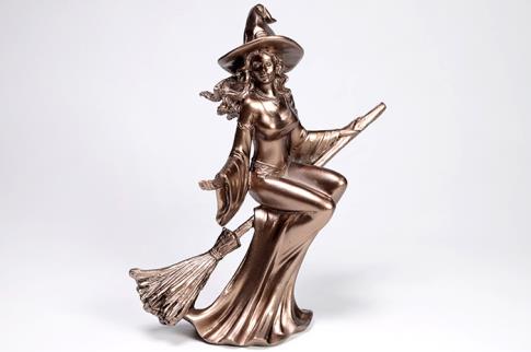 COMODIN | FIGURA BRUJA MONTADA SOBRE ESCOBA COLOR DORADO 19X16 CM.
