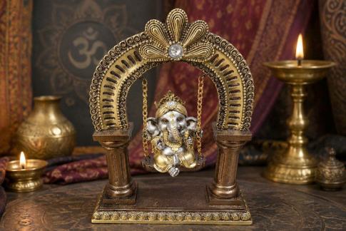 COMODIN | FIGURA GANESHA SENTADA SOBRE COLUMPIO EN ARCO CON COLUMNAS COLOR DORADO, PLATEADO Y COBRE 22 X 15,5 CM.